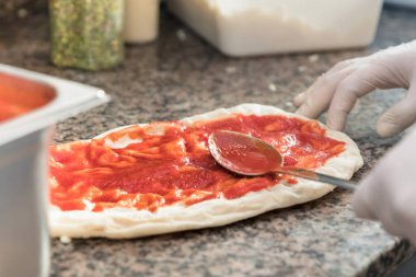 Taze orijinal İtalyan ham pizza hamur hazırlama, geleneksel tarzda. Domates sosu uygulama.