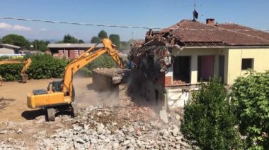 Demolition work house. Excavator demolishing house for new construction project. Bergamo, ITALY - August 1, 2022.