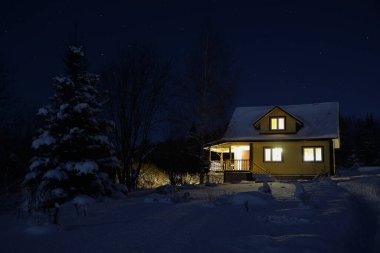 Aydınlatılmış ahşap ev açık kış akşamında
