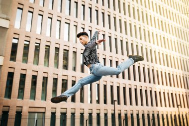 Genç adam sokakta zıplıyor ve dans ediyor.