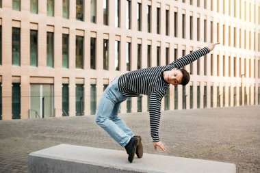 Genç adam sokak bankında akrobatik dans yapıyor.