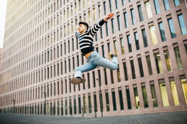 Genç adam sokakta zıplıyor.