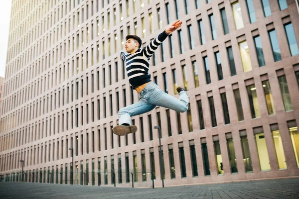 Genç adam sokakta zıplıyor.