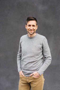 Gri bir arka planda, sıradan giyinmiş bir adamın portresi.