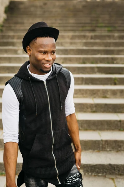 Siyah şapkalı genç bir erkek sokakta merdivenlerden iniyor.