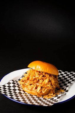 Pulled chicken burger over a black background