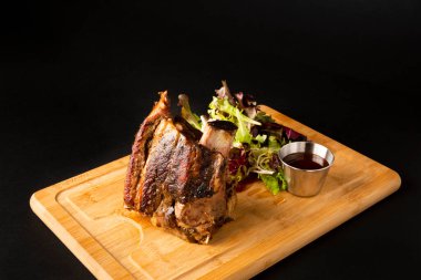 Big piece of beef rib on a wooden table over a black background