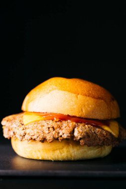 Doble cheeseburger with melted cheese and ketchup over a black background