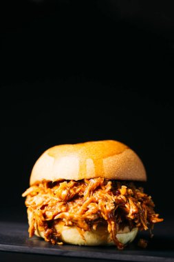 Pulled chicken burger over a black background