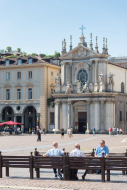 Torino, İtalya. 10 Haziran 2021. Tarihi binaların ve Santa Cristina Kilisesi 'nin manzarası. Yaşlı insanlar banklarda oturuyor..