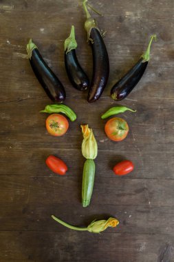 Eski ahşap bir masada taze sebzelerle yapılmış komik bir gülen yüz. Sağlıklı beslenme ve mutluluk kavramı.