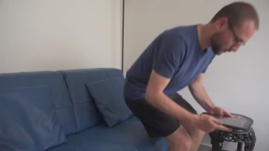 Kanepede oturan gözlüklü bir adam tableti açar ve büyük bir memnuniyet ve sevinçle olumlu bir sonuç görür. Pozitif sonuç kavramı, büyük mutluluk ve memnuniyet.