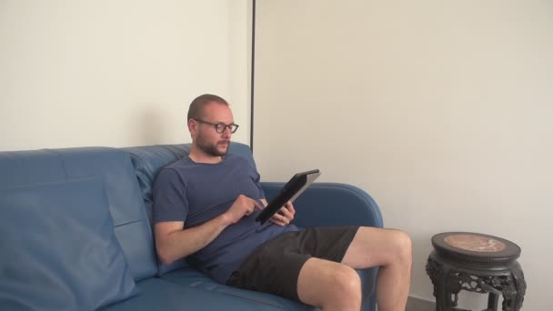 Mann Mit Brille Sitzt Auf Dem Sofa Und Entspannt Sich — Stockvideo