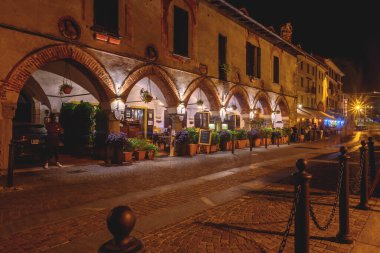 Arona, İtalya. Piazza del Popolo 'daki tarihi bir binanın ön cephesinin kemerlerine gece bakın. 10 Haziran 2022.