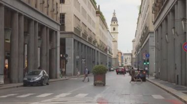 Torino, İtalya. Via Roma 'daki araba trafiği ve caddeden geçen insanların görüntüsü. Uzakta San Carlo Borromeo Kilisesi çan kulesi. Panning efektli zaman ayarlı video. 21 Haziran 2022.