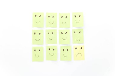 Başkalarının arasında üzgün olmanın kavramsal tasviri. Memnun oldum, hayal kırıklığına uğradım. Beyaz arkaplanda yeşil ve sarı yapışkan notlar.