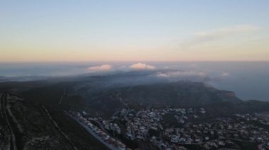 Cumbre del Sol 'da sisli gün batımı. Sis ufku ve kıyı şeridini gizliyor. İspanya, Alicante 'deki Benitachell, Moraira, Calpe ve Javea' dan insansız hava aracı görüntüleri