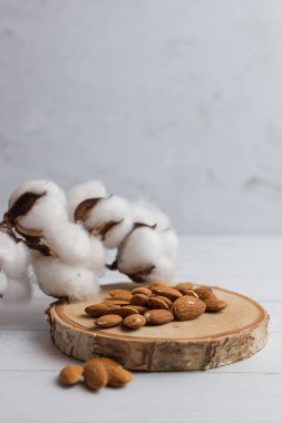 Bagajda bir avuç dolusu badem var. Bagajda bademlerle birlikte bir pamuk dalı var. Dikey resim.