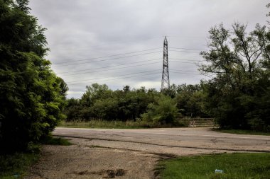 Arka planda bir korulukta bir antenle yol ve toprak yol arasında kırsal kesişiyor.