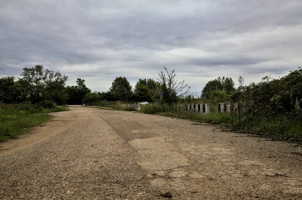 İtalya kırsalındaki tarlaların yanındaki çakıl yolu Sonbaharda bulutlu bir günde