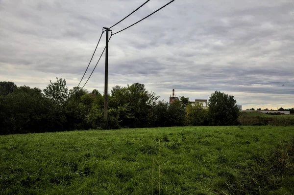 İtalya kırsalında sonbaharda bulutlu bir günde elektrik direkleri ve ağaçlarla dolu bir alan.