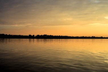 Sonbaharda uzak bir ormanın olduğu bir gölün üzerinde gün batımı
