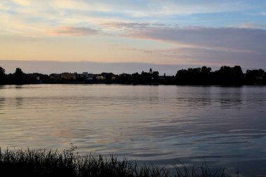 Sonbaharda uzak bir ormanın olduğu bir gölün üzerinde gün batımı