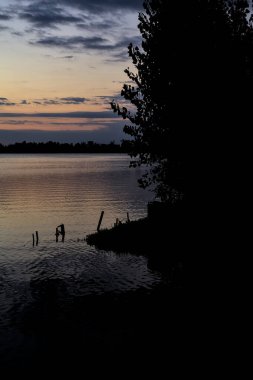 Sonbaharda ağaçlarla çevrili bir gölün üzerinde gün batımı