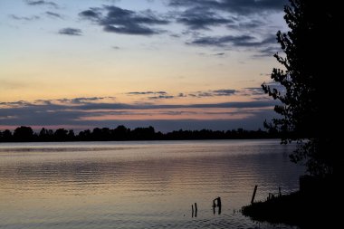 Sonbaharda ağaçlarla çevrili bir gölün üzerinde gün batımı