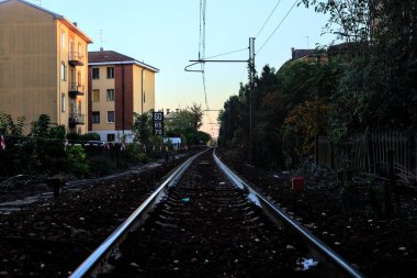 Gün batımında bir yerleşim alanının ortasında demiryolu hattı.