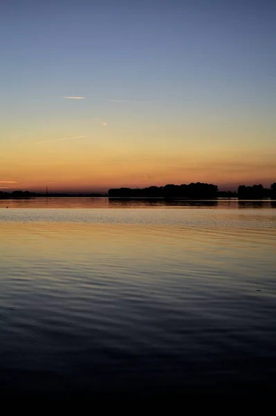 背景に森のある湖の上の夕日 — ストック写真