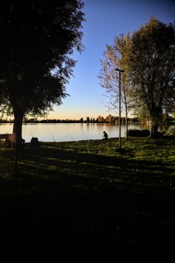 Sonbaharda alacakaranlıkta nehir kenarında bir balıkçı.