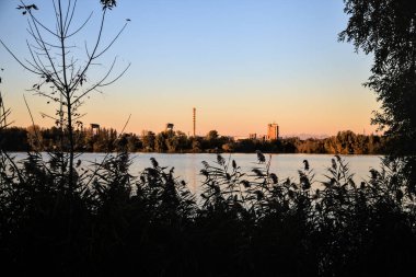 Alacakaranlıkta göl ve karşı kıyıda bir park.