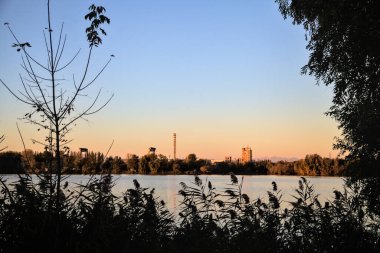 Alacakaranlıkta göl ve karşı kıyıda bir park.