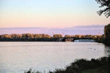 Alacakaranlıkta göl ve karşı kıyıda bir park.