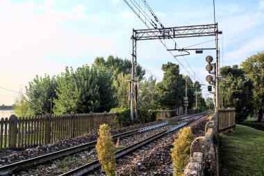 Gün batımında bir gölün kıyısındaki tren yolu.