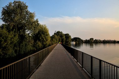 Gün batımında ağaçlarla çevrili bir göldeki geçit.