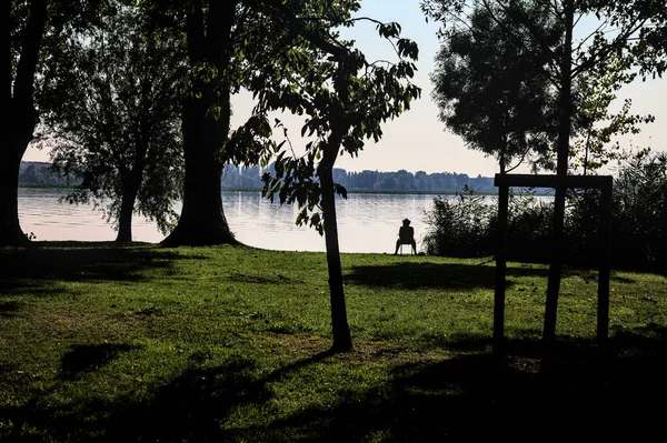 日落时 渔夫坐在公园的湖边 — 图库照片