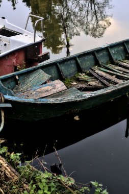 Bulutlu bir günde, bir gölün kıyısında demirli bir tekne