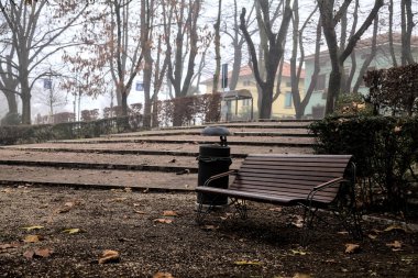 Sisli bir günde, bir parkta yanında banklar olan merdivenler.