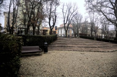 Sisli bir günde, bir parkta yanında banklar olan merdivenler.