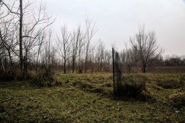 Broken fence in a bare field in the countryside on a cloudy day