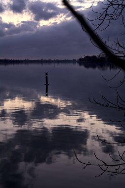Bulutlu göl ve alacakaranlıkta gökyüzü suya dökülüyor.