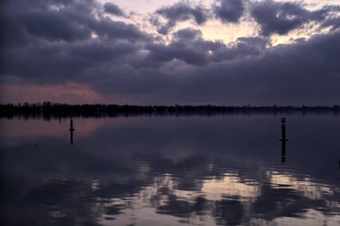 Bulutlu göl ve alacakaranlıkta gökyüzü suya dökülüyor.