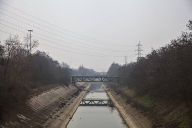 Bulutlu bir günde kışın ağaçlarla çevrili eğlence kanalı