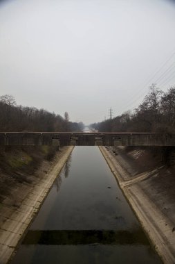 Bulutlu bir günde kışın ağaçlarla çevrili eğlence kanalı