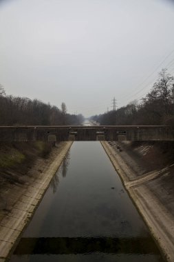Bulutlu bir günde kışın ağaçlarla çevrili eğlence kanalı