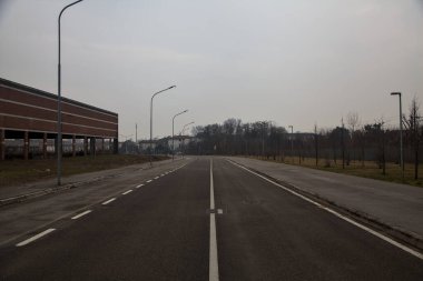 Bulutlu bir günde kırsalda terk edilmiş bir deponun yanındaki boş yol.