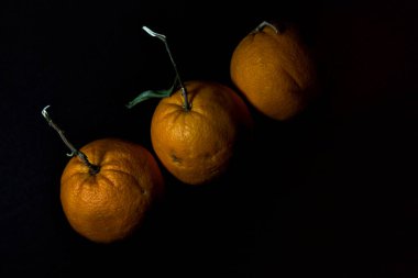 Siyah bir zemin üzerine üç portakal