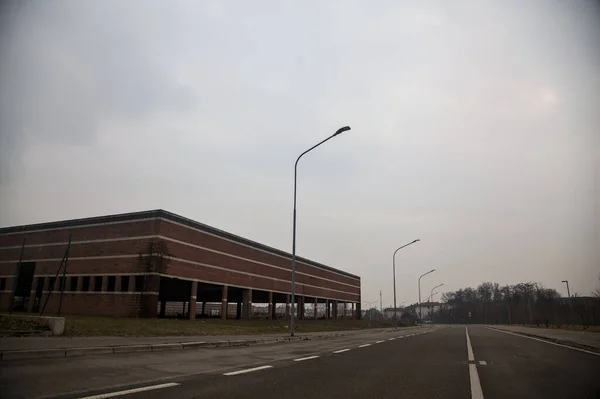 曇りの日に田舎の放棄された倉庫の隣の空の道 — ストック写真